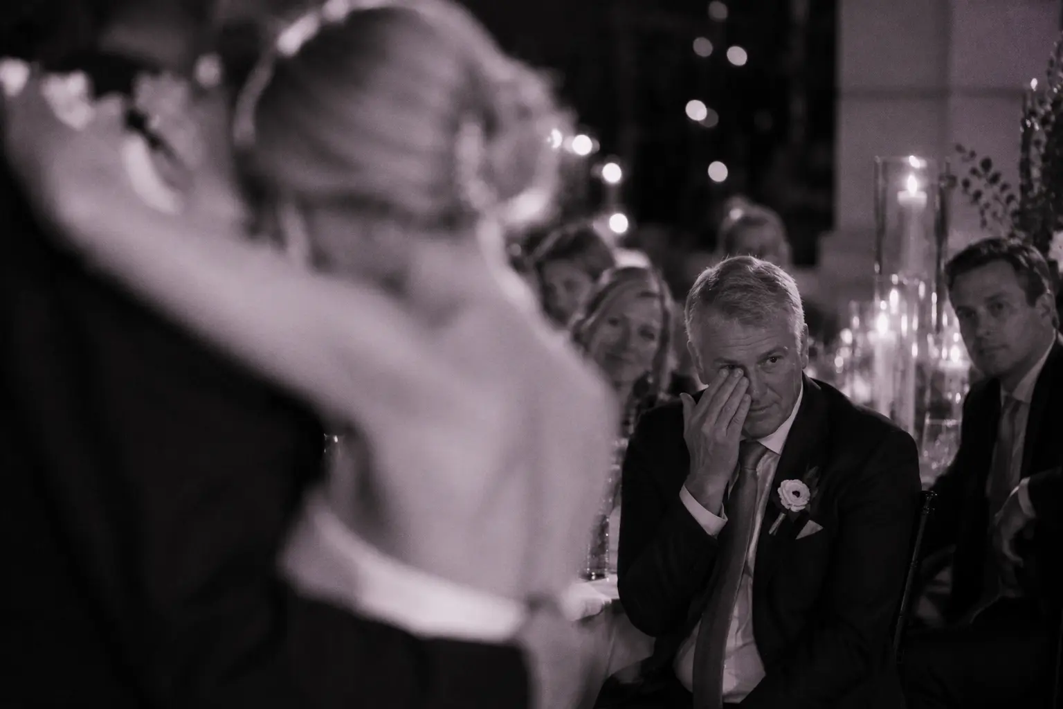 A father wiping away a tear as he watches the first dance.